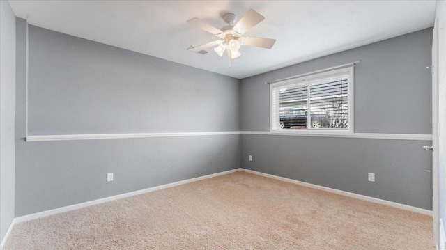 carpeted spare room featuring baseboards and a ceiling fan