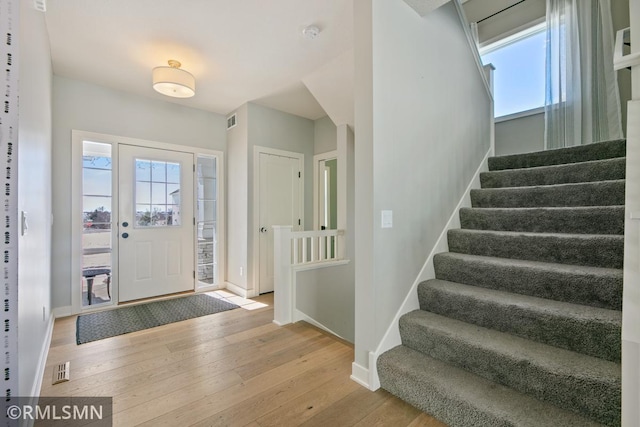 foyer featuring light wood-style floors, visible vents, stairway, and baseboards