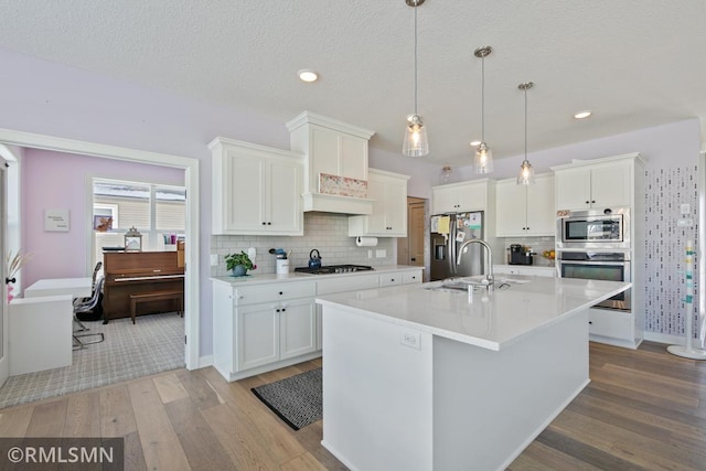 kitchen with stainless steel appliances, light countertops, a sink, and white cabinetry