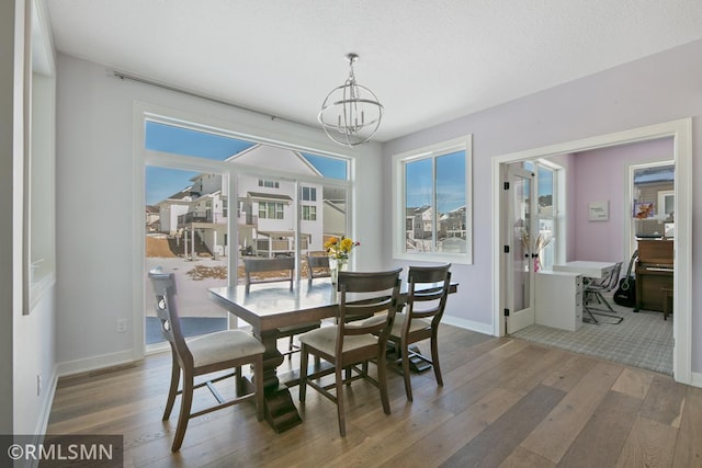 dining area with baseboards, french doors, hardwood / wood-style flooring, and a notable chandelier