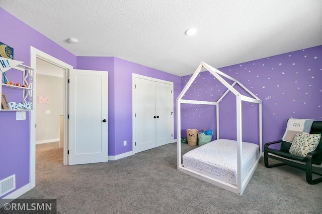 bedroom with a textured ceiling, carpet flooring, visible vents, and baseboards