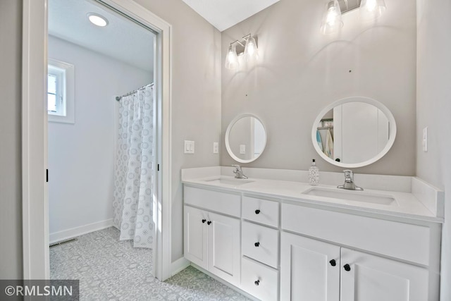 full bath with visible vents, a sink, baseboards, and double vanity