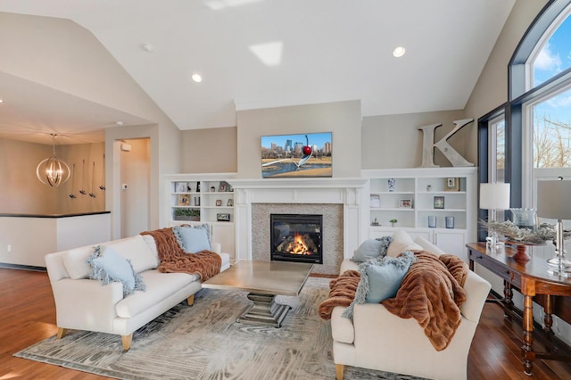 living room featuring lofted ceiling, recessed lighting, an inviting chandelier, a glass covered fireplace, and wood finished floors