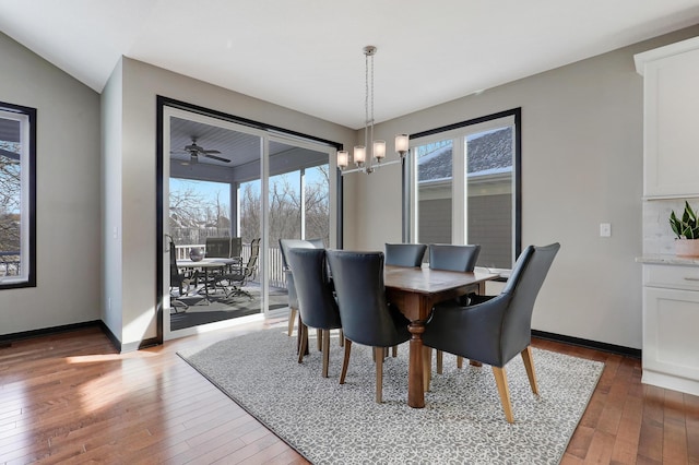 dining room featuring dark wood-style floors, baseboards, and an inviting chandelier