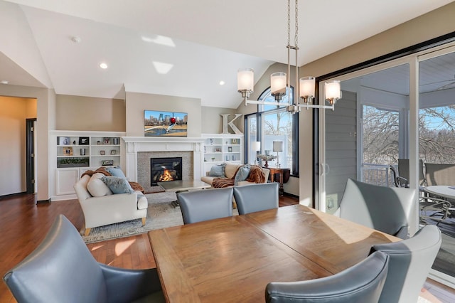 dining space with a notable chandelier, recessed lighting, a high end fireplace, vaulted ceiling, and dark wood-style floors