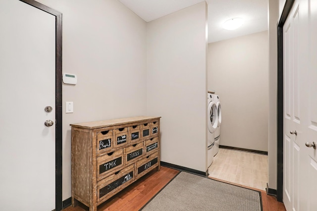 laundry area with laundry area, washing machine and dryer, baseboards, and dark wood-type flooring