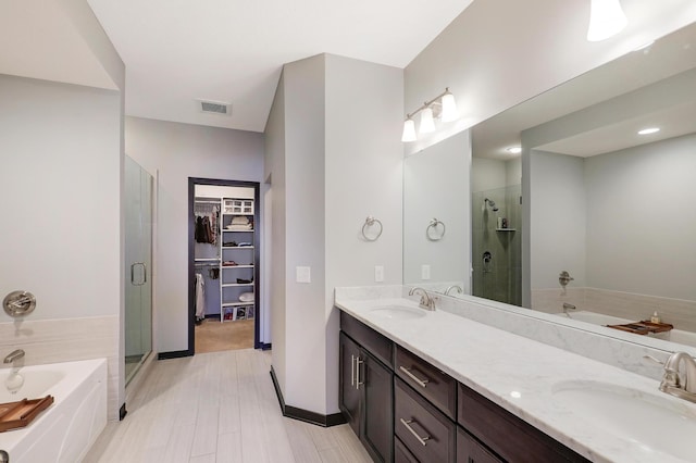 full bathroom featuring a garden tub, a sink, visible vents, a spacious closet, and double vanity