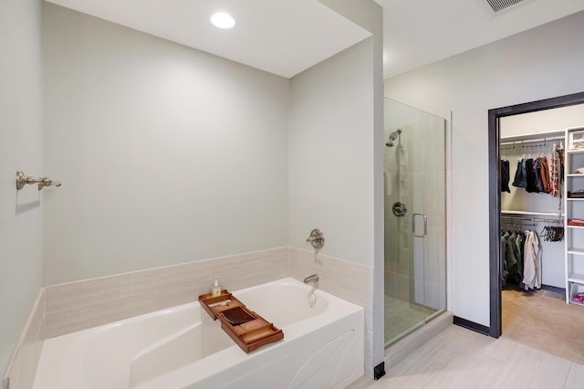 bathroom featuring a stall shower, a walk in closet, a garden tub, and recessed lighting