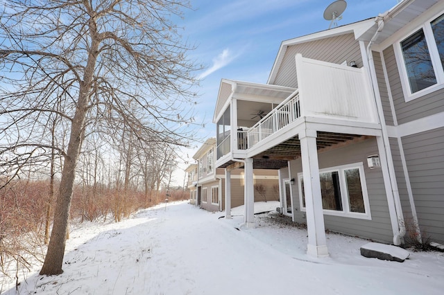 snow covered property with a balcony and ceiling fan