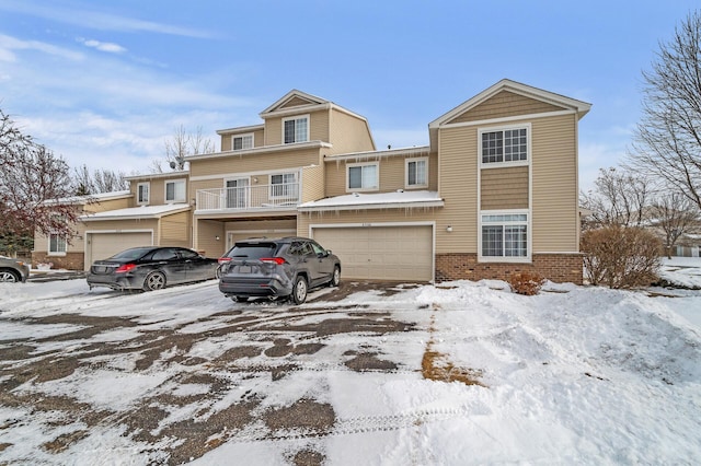 townhome / multi-family property with a garage and brick siding