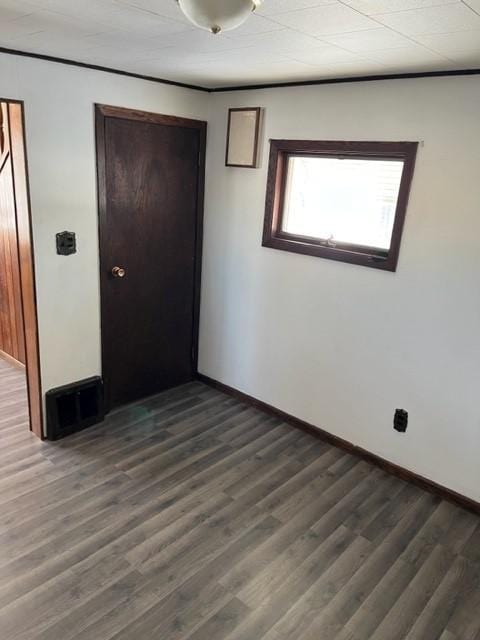 empty room featuring baseboards and dark wood-type flooring