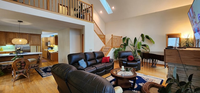 living room featuring high vaulted ceiling, stairway, and light wood-style flooring