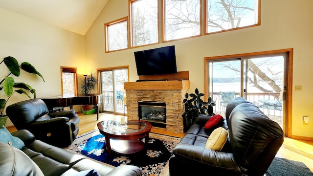 living area featuring high vaulted ceiling, baseboards, wood finished floors, and a fireplace