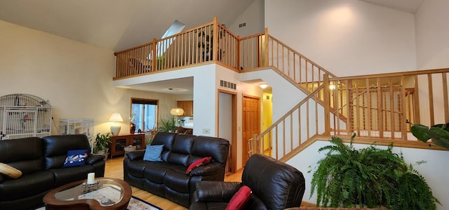 living area featuring a towering ceiling, wood finished floors, visible vents, and stairs