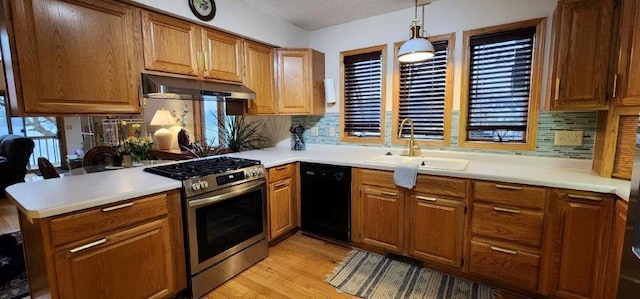 kitchen featuring a sink, gas stove, backsplash, under cabinet range hood, and black dishwasher