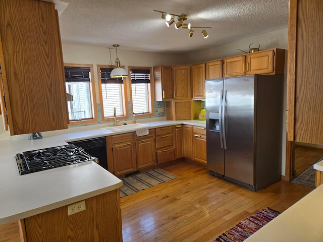kitchen featuring cooktop, a sink, a textured ceiling, light wood-style floors, and stainless steel fridge with ice dispenser