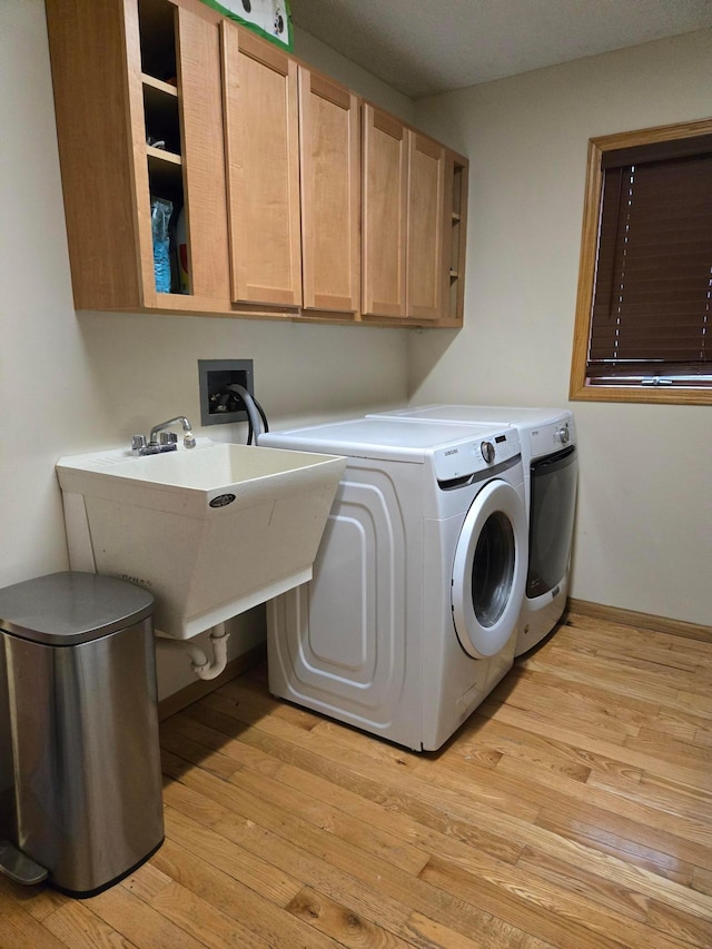 laundry room with cabinet space, independent washer and dryer, and light wood-style flooring