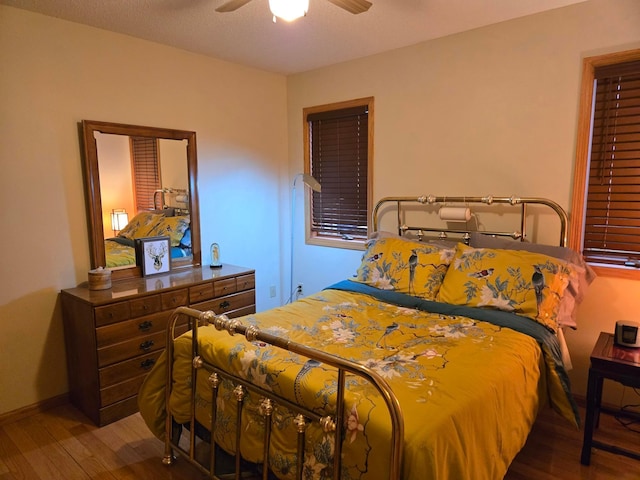 bedroom featuring wood finished floors, a ceiling fan, and baseboards