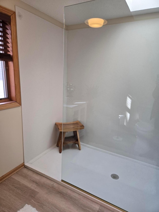 full bath featuring baseboards, wood finished floors, and a shower