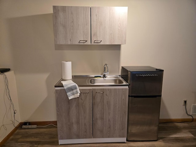 kitchen with modern cabinets, wood finished floors, a sink, and freestanding refrigerator