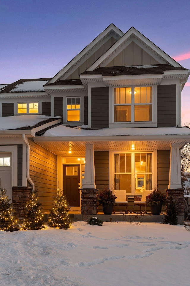 craftsman house with stone siding, a porch, and board and batten siding