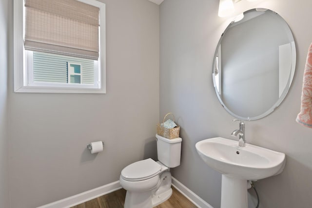 bathroom with toilet, baseboards, and wood finished floors