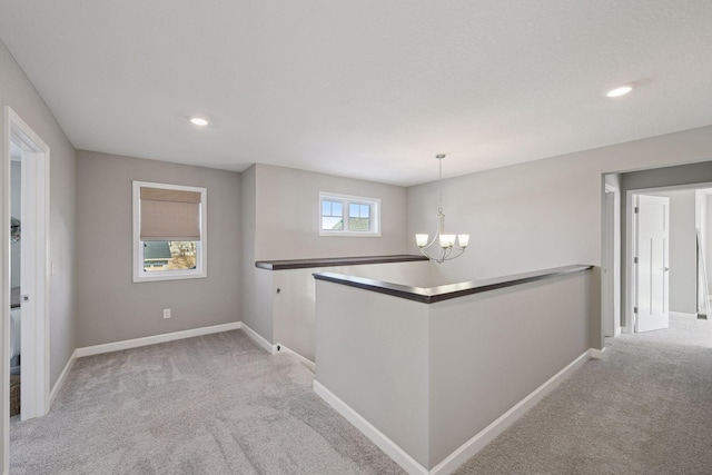 corridor featuring light carpet, recessed lighting, baseboards, and an inviting chandelier