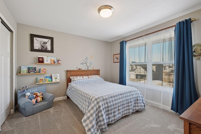 bedroom with carpet, a closet, a textured ceiling, and baseboards