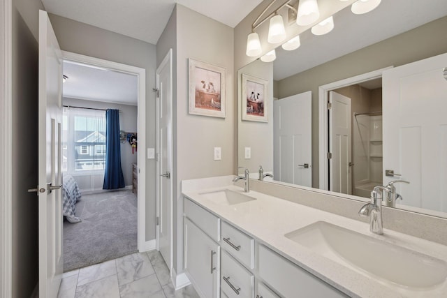 full bathroom with marble finish floor, double vanity, a sink, and baseboards