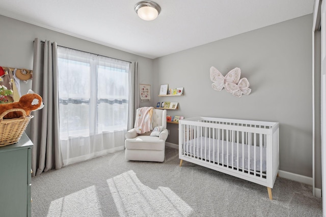 bedroom featuring carpet flooring, a crib, and baseboards