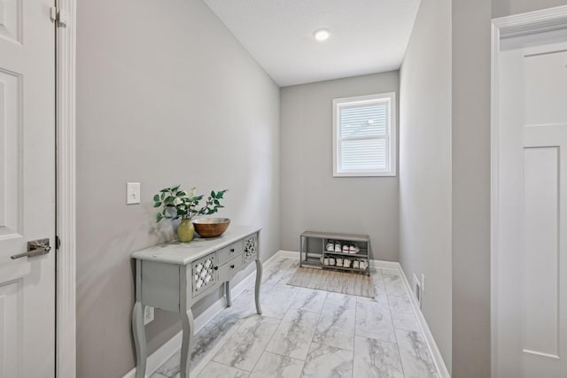 entryway featuring marble finish floor, a textured ceiling, and baseboards