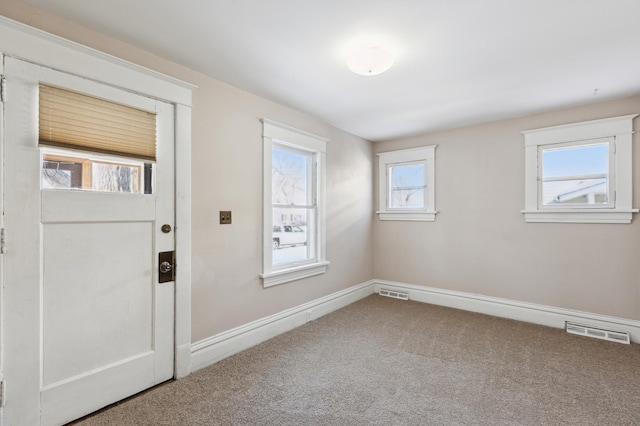 foyer entrance with carpet, visible vents, and baseboards