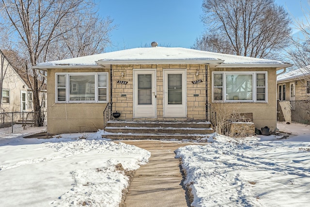 bungalow with entry steps, stone siding, and stucco siding