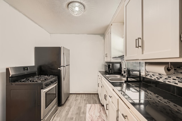 kitchen featuring stainless steel gas stove, dark countertops, white cabinetry, and a sink