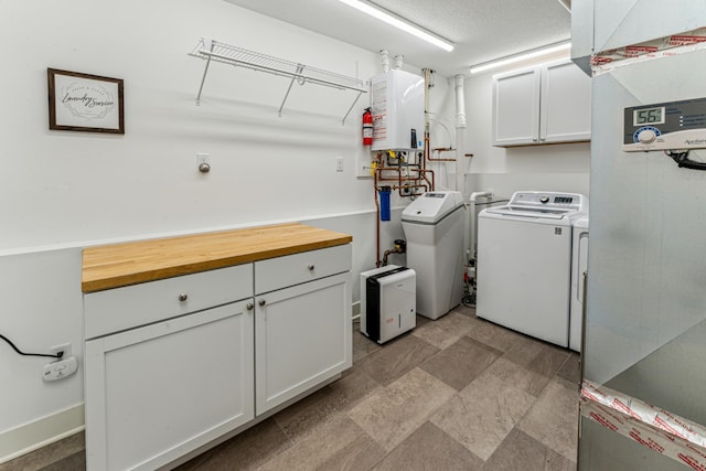 clothes washing area featuring stone finish flooring, washing machine and dryer, and cabinet space