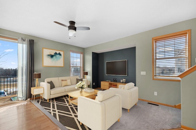 living room with visible vents, baseboards, and ceiling fan