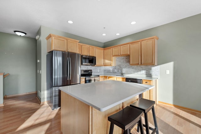 kitchen with light brown cabinetry, appliances with stainless steel finishes, tasteful backsplash, and a sink