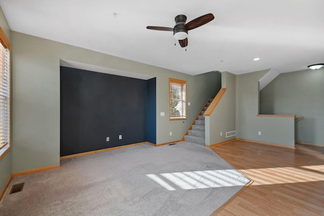 living room with wood finished floors, baseboards, visible vents, ceiling fan, and stairs