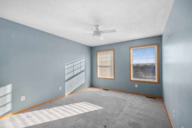 empty room featuring visible vents, ceiling fan, baseboards, carpet floors, and a textured ceiling