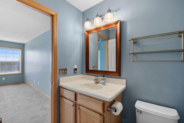 bathroom with a textured ceiling, toilet, vanity, and baseboards