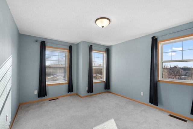 spare room featuring visible vents, baseboards, and carpet