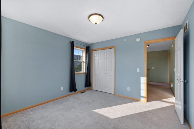 unfurnished bedroom with baseboards, visible vents, carpet floors, and a closet