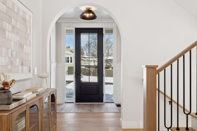 foyer entrance with wood finished floors, arched walkways, and stairs