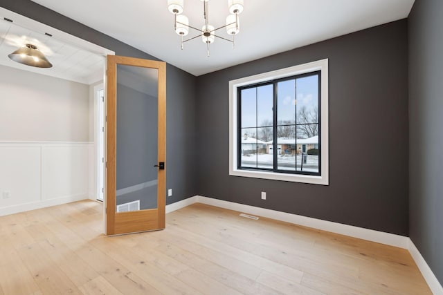 spare room featuring a chandelier and wood finished floors
