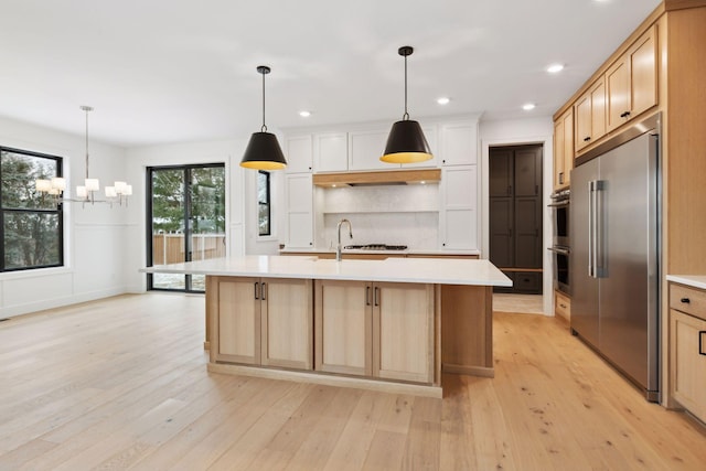 kitchen with appliances with stainless steel finishes, light countertops, a chandelier, light wood-type flooring, and recessed lighting
