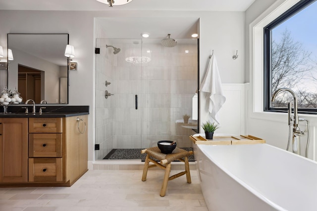 full bathroom with a stall shower, a freestanding tub, vanity, and recessed lighting
