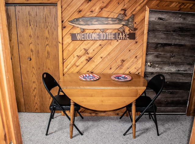 carpeted dining space with wooden walls