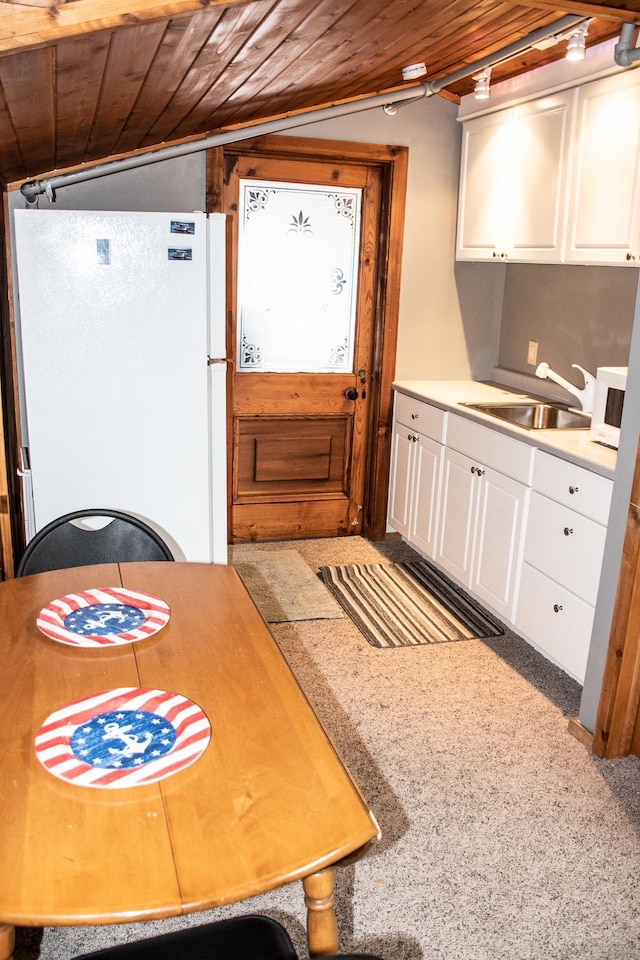 kitchen with white appliances, white cabinets, wooden ceiling, light countertops, and a sink