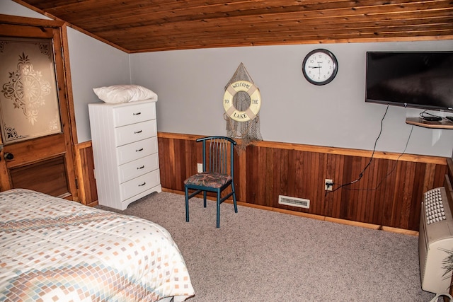 bedroom with a wainscoted wall, lofted ceiling, light colored carpet, visible vents, and wood ceiling