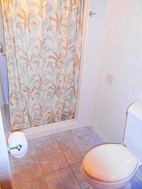 full bathroom with a shower stall, toilet, and tile patterned floors